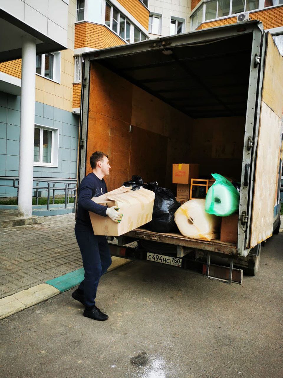 Грузчик загружает коробку в фургон